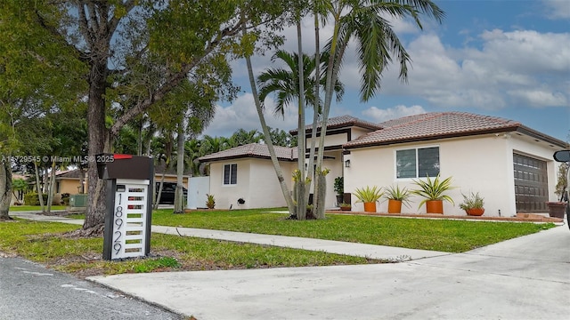 view of front of property featuring a garage, stucco siding, a tiled roof, and a front yard