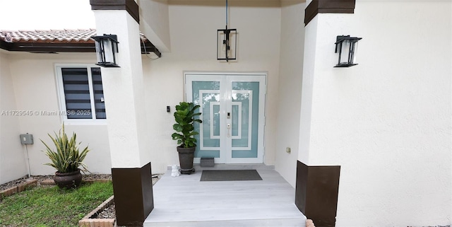 entrance to property with a tile roof, french doors, and stucco siding