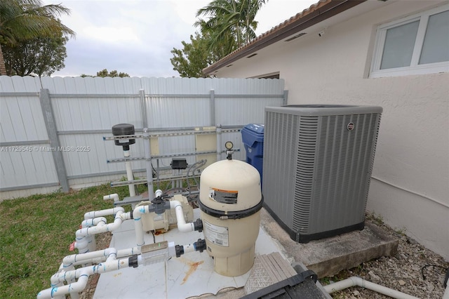 details featuring central AC unit, pump, fence, and stucco siding