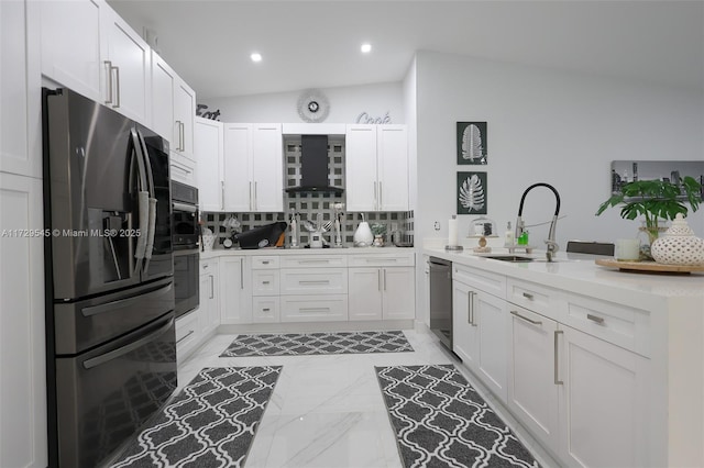 kitchen with lofted ceiling, appliances with stainless steel finishes, a peninsula, wall chimney range hood, and a sink