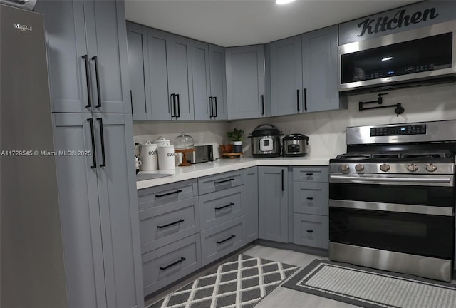 kitchen with appliances with stainless steel finishes, gray cabinets, and light countertops