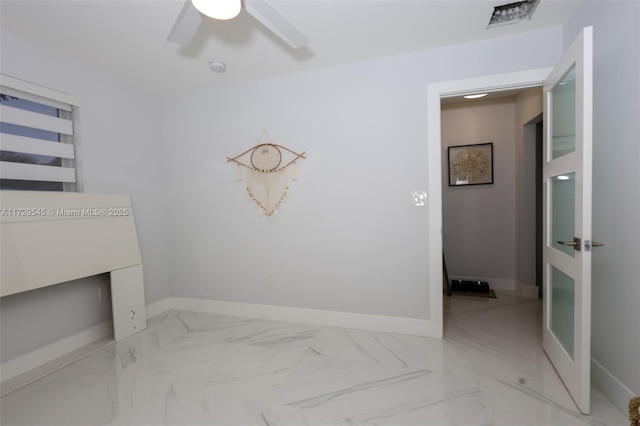 interior space featuring marble finish floor, ceiling fan, and baseboards