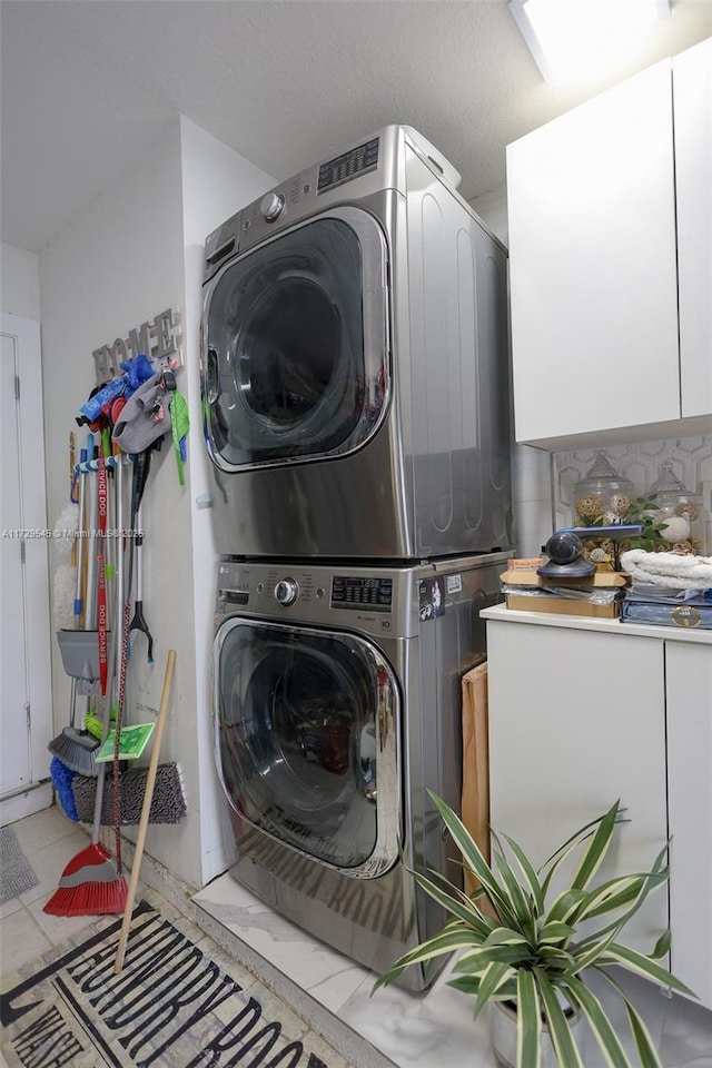 washroom with cabinet space and stacked washer and clothes dryer