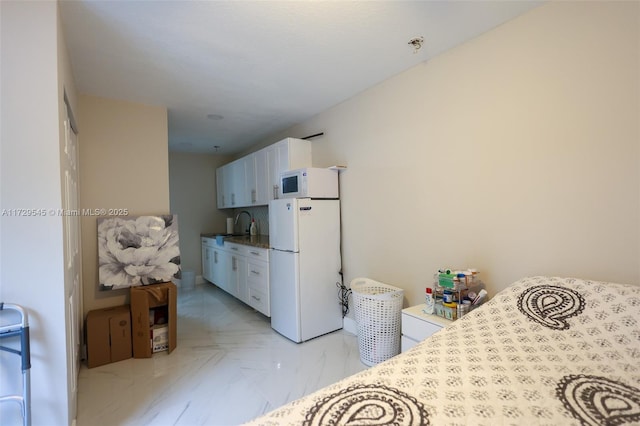 kitchen with white appliances, marble finish floor, white cabinets, and a sink