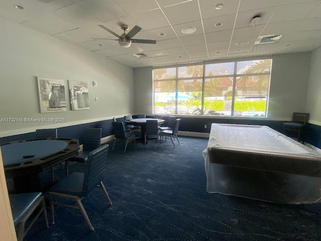 carpeted office space with ceiling fan and a drop ceiling