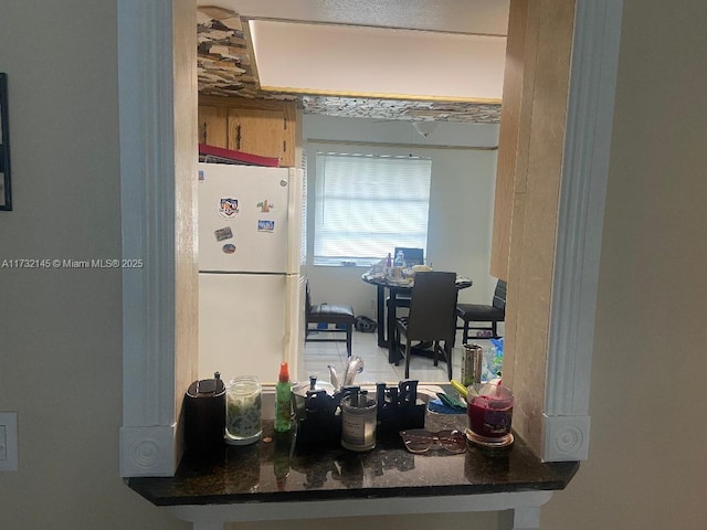 kitchen featuring dark stone countertops and white fridge