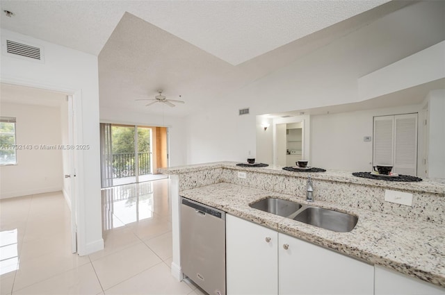 kitchen with lofted ceiling, sink, dishwasher, white cabinetry, and light stone countertops