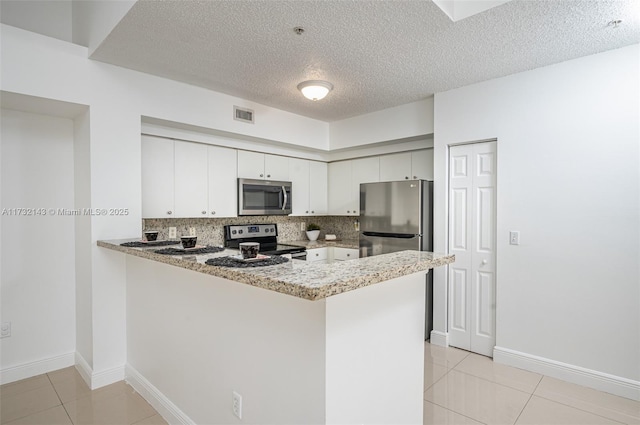 kitchen with appliances with stainless steel finishes, white cabinets, light tile patterned flooring, decorative backsplash, and kitchen peninsula