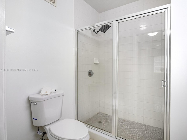 bathroom with a shower with door and toilet