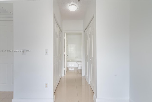 hallway featuring a textured ceiling and light tile patterned flooring