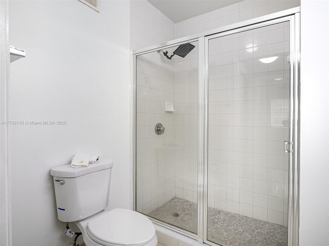 bathroom featuring a shower with shower door and toilet