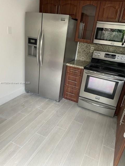 kitchen featuring stainless steel appliances, light stone countertops, and backsplash