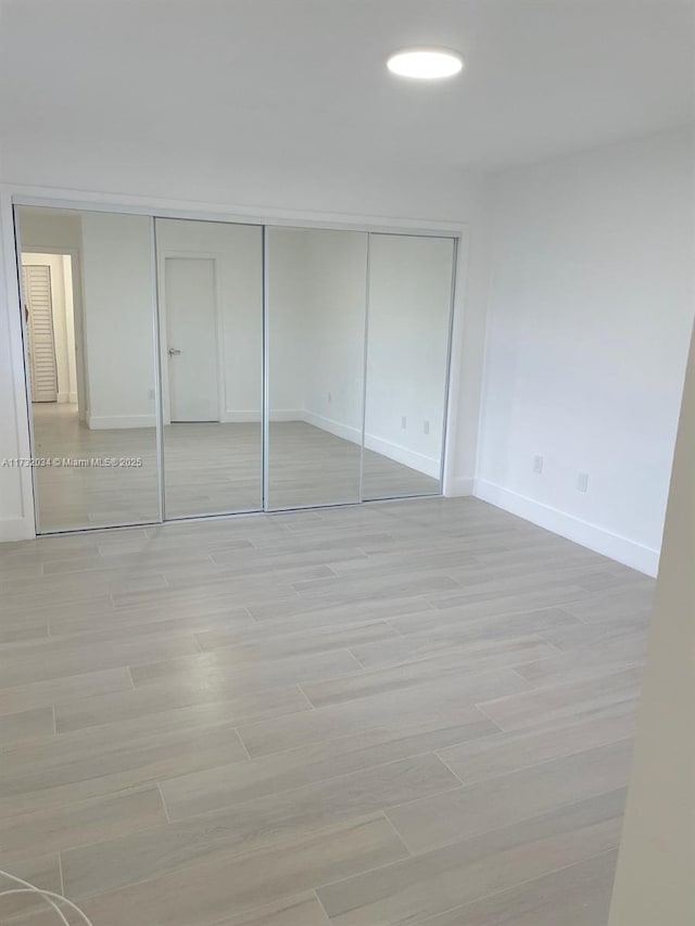 unfurnished bedroom featuring a closet and light wood-type flooring