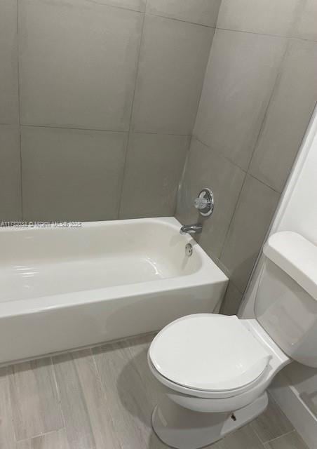 bathroom featuring tub / shower combination and toilet