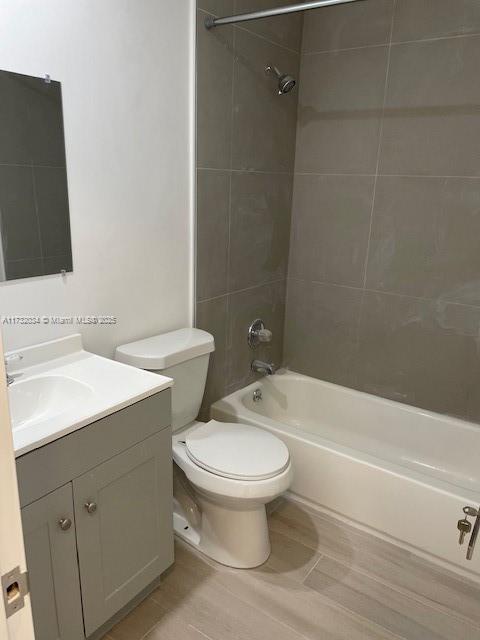 full bathroom featuring tiled shower / bath combo, vanity, and toilet