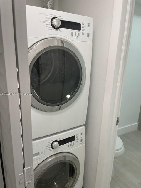 clothes washing area with stacked washing maching and dryer