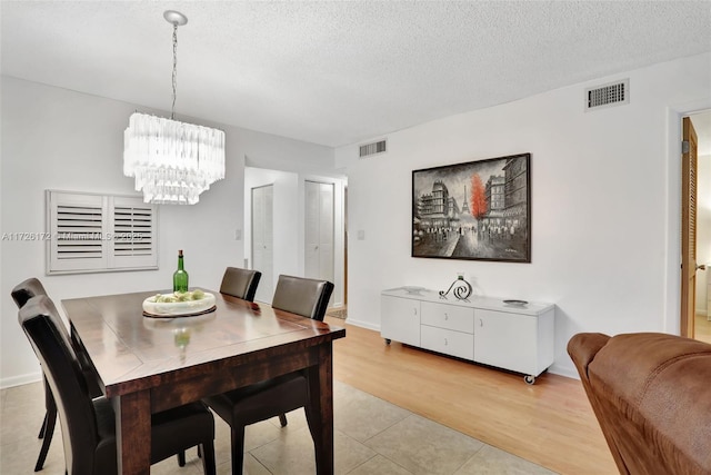 dining area featuring an inviting chandelier, a textured ceiling, and light tile patterned floors