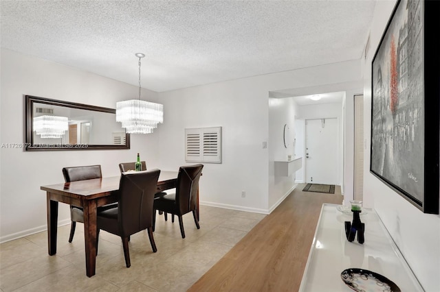 dining area with light tile patterned floors, a textured ceiling, and an inviting chandelier