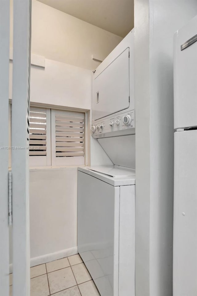 washroom with light tile patterned flooring and stacked washing maching and dryer