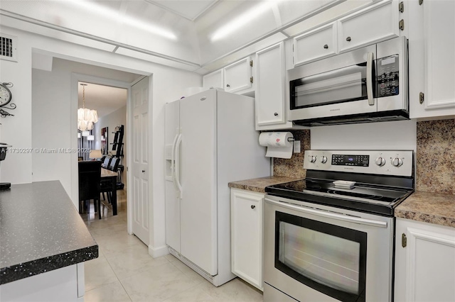 kitchen featuring stainless steel appliances, light tile patterned floors, white cabinets, and decorative backsplash