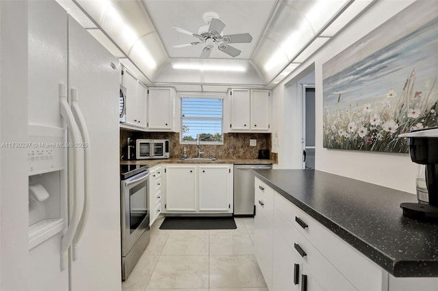 kitchen featuring lofted ceiling, sink, light tile patterned floors, stainless steel appliances, and white cabinets