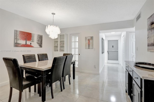 tiled dining space with a notable chandelier, sink, and a textured ceiling