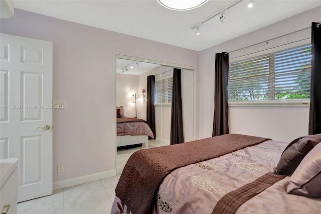 bedroom featuring light tile patterned floors, track lighting, and a closet