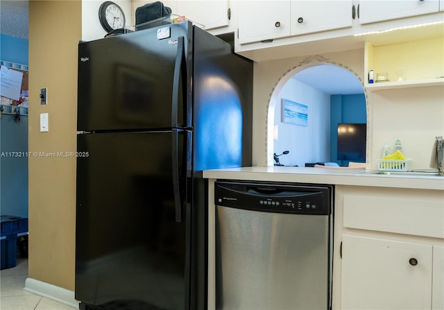 kitchen featuring light tile patterned flooring, black refrigerator, sink, white cabinets, and stainless steel dishwasher