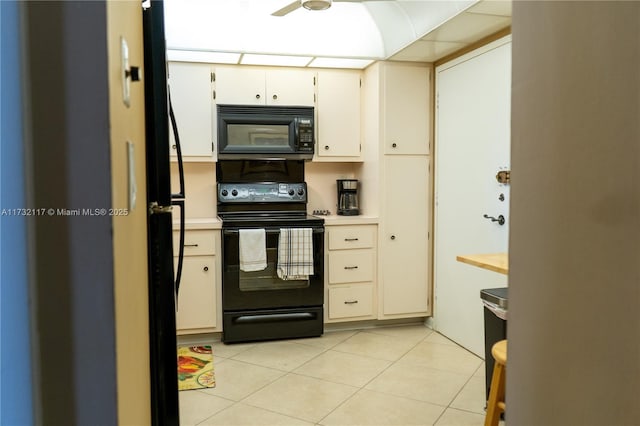 kitchen featuring white cabinetry, light tile patterned floors, and black appliances