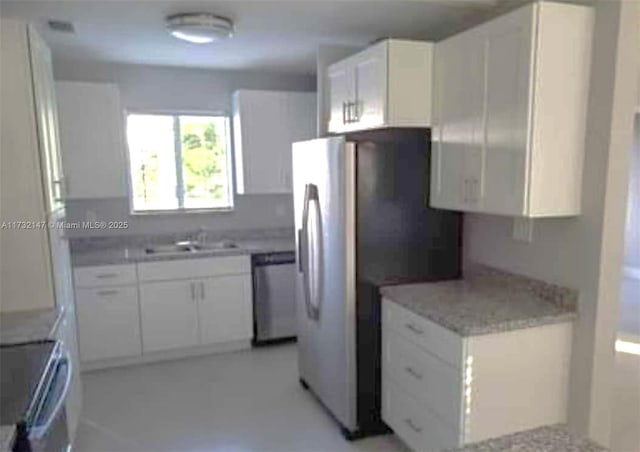 kitchen featuring sink, light stone counters, range, stainless steel dishwasher, and white cabinets