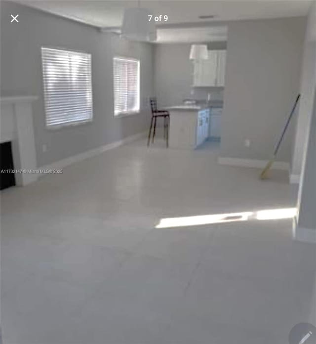 kitchen featuring light countertops, white cabinets, a fireplace, and baseboards