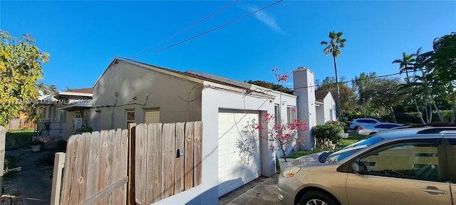 view of home's exterior with an attached garage, fence, and stucco siding