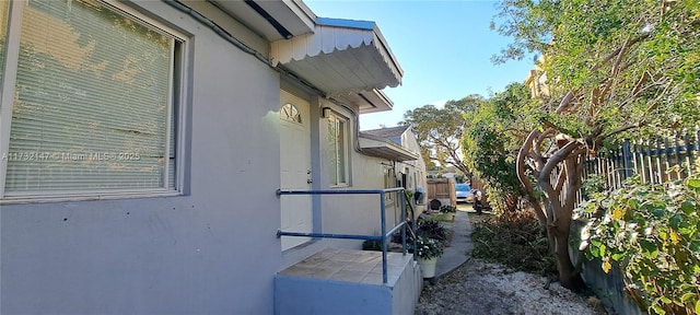 view of side of home with fence and stucco siding