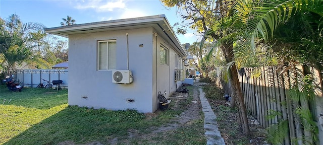 view of side of property with ac unit, a lawn, a fenced backyard, and stucco siding