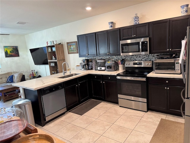 kitchen with sink, light tile patterned floors, appliances with stainless steel finishes, kitchen peninsula, and backsplash