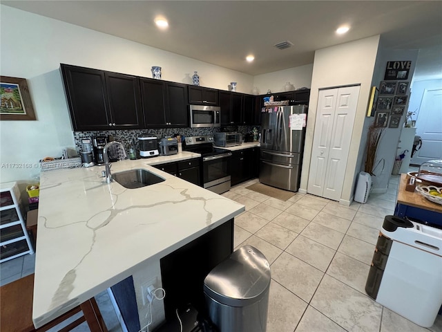 kitchen with sink, light stone countertops, kitchen peninsula, and appliances with stainless steel finishes