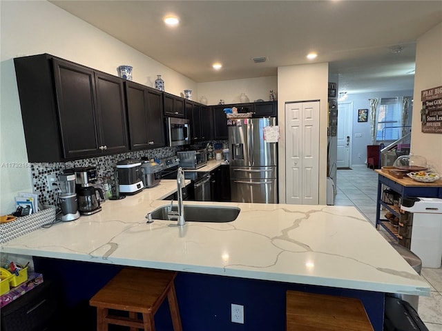 kitchen featuring appliances with stainless steel finishes, sink, a kitchen bar, and kitchen peninsula