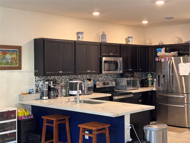 kitchen with sink, a breakfast bar area, kitchen peninsula, stainless steel appliances, and backsplash