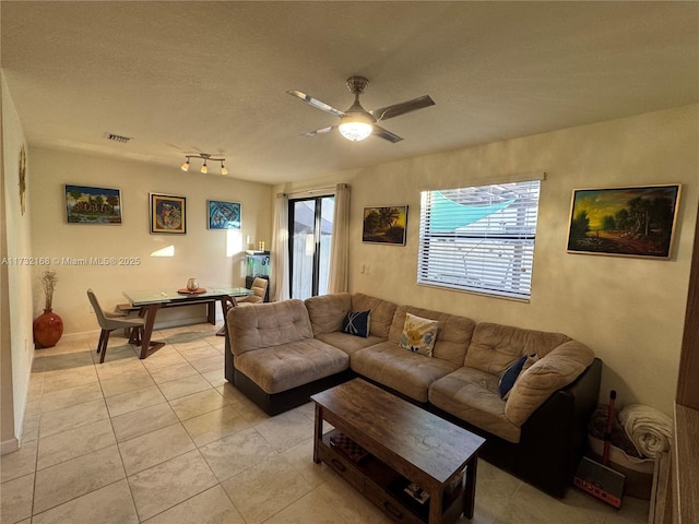 living room with ceiling fan, a textured ceiling, and light tile patterned floors