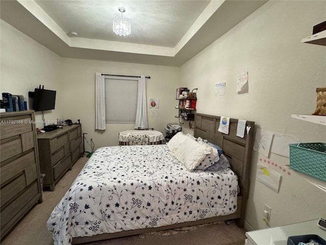 bedroom with a raised ceiling and light carpet