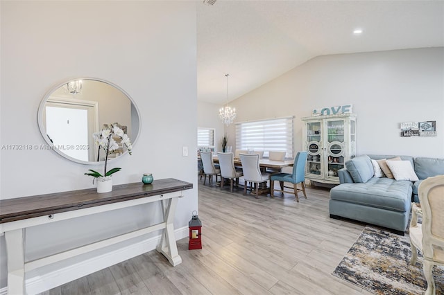 living room featuring a notable chandelier, vaulted ceiling, and light hardwood / wood-style floors