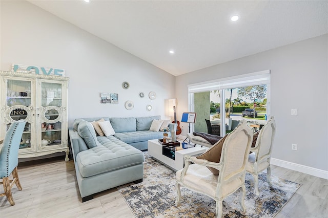 living room with high vaulted ceiling and light hardwood / wood-style flooring