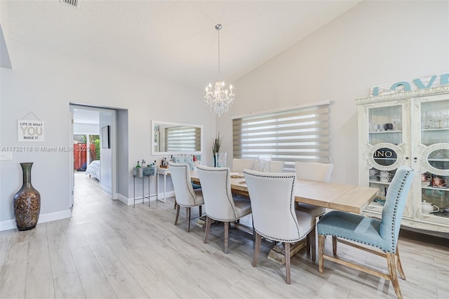 dining area with high vaulted ceiling, a chandelier, and light wood-type flooring