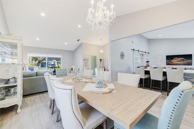 dining area featuring lofted ceiling, a barn door, light hardwood / wood-style flooring, and a notable chandelier