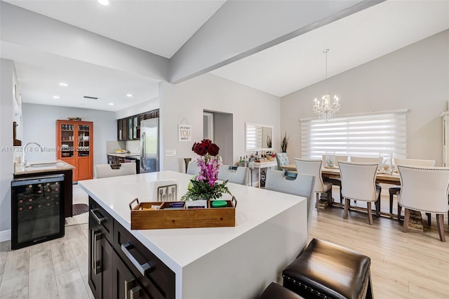 kitchen with lofted ceiling, sink, stainless steel fridge, a center island, and beverage cooler