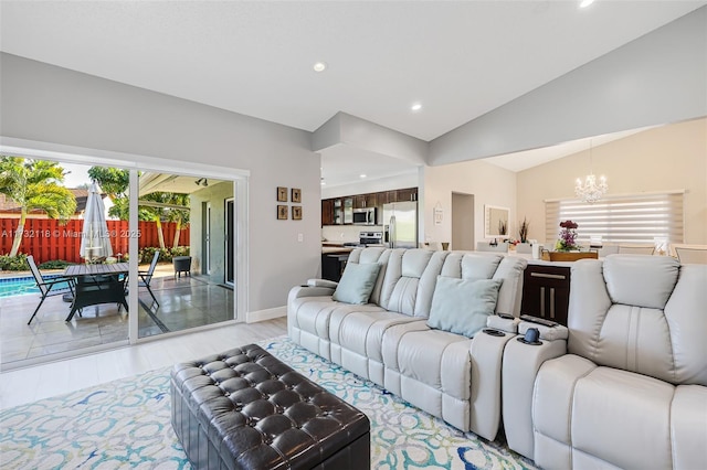 living room featuring an inviting chandelier, vaulted ceiling, and light wood-type flooring