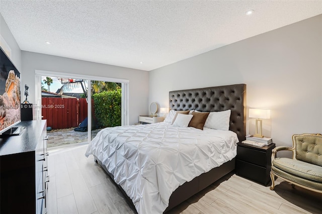 bedroom featuring access to exterior, hardwood / wood-style floors, and a textured ceiling