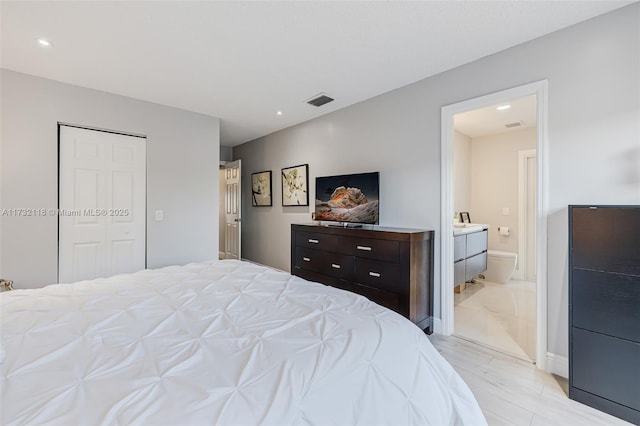 bedroom with light wood-type flooring, ensuite bath, and a closet