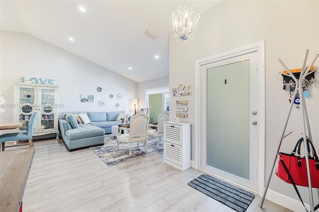 living room featuring an inviting chandelier, vaulted ceiling, and light hardwood / wood-style floors