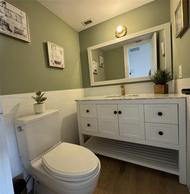 bathroom featuring hardwood / wood-style flooring, vanity, tile walls, and toilet